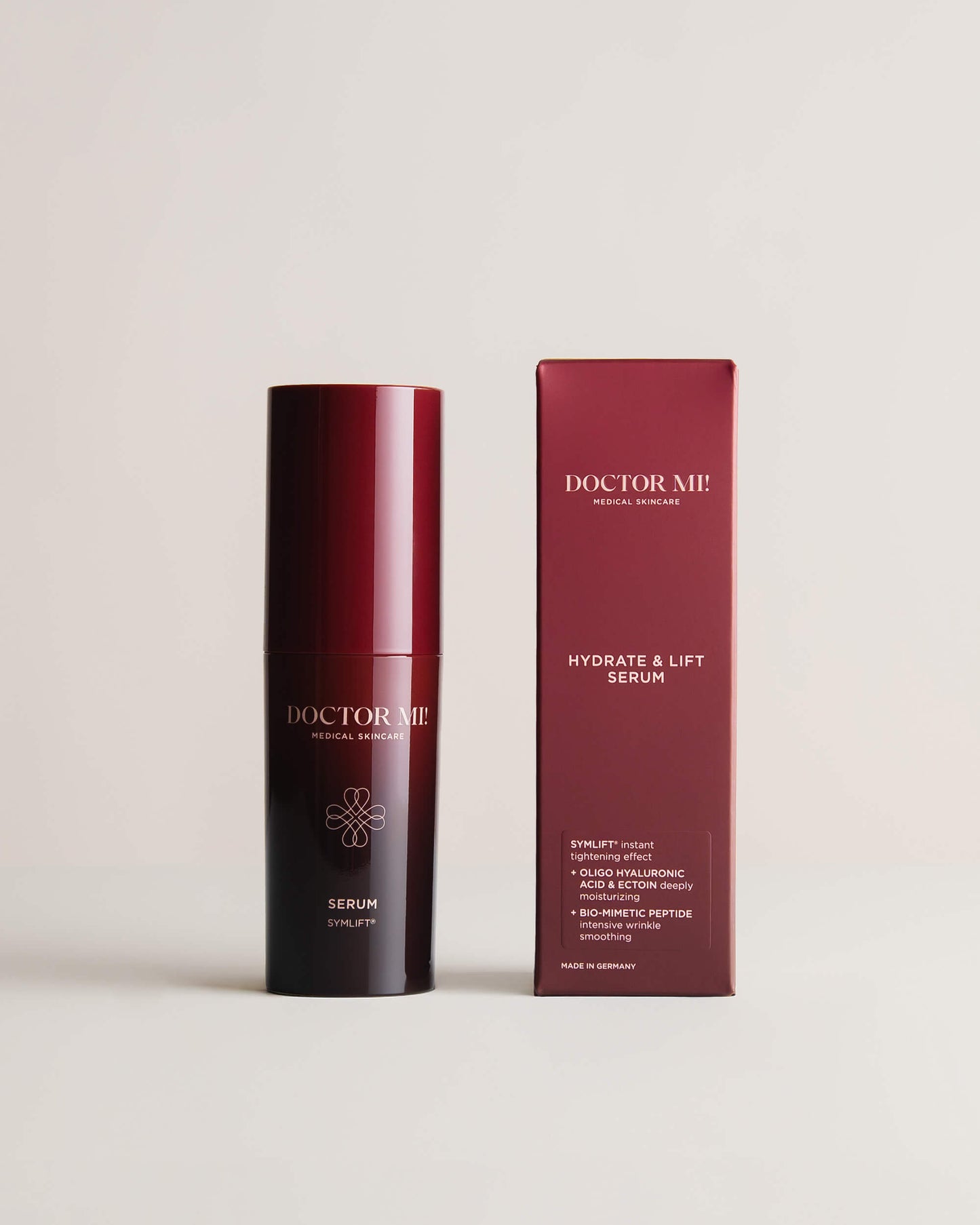 DOCTOR MI! HYDRATE & LIFT SERUM Feuchtigkeits-Serum mit Straffungseffekt für intensive Faltenglättung in roten Pumpspender neben roter Verpackung auf grauem Hintergrund