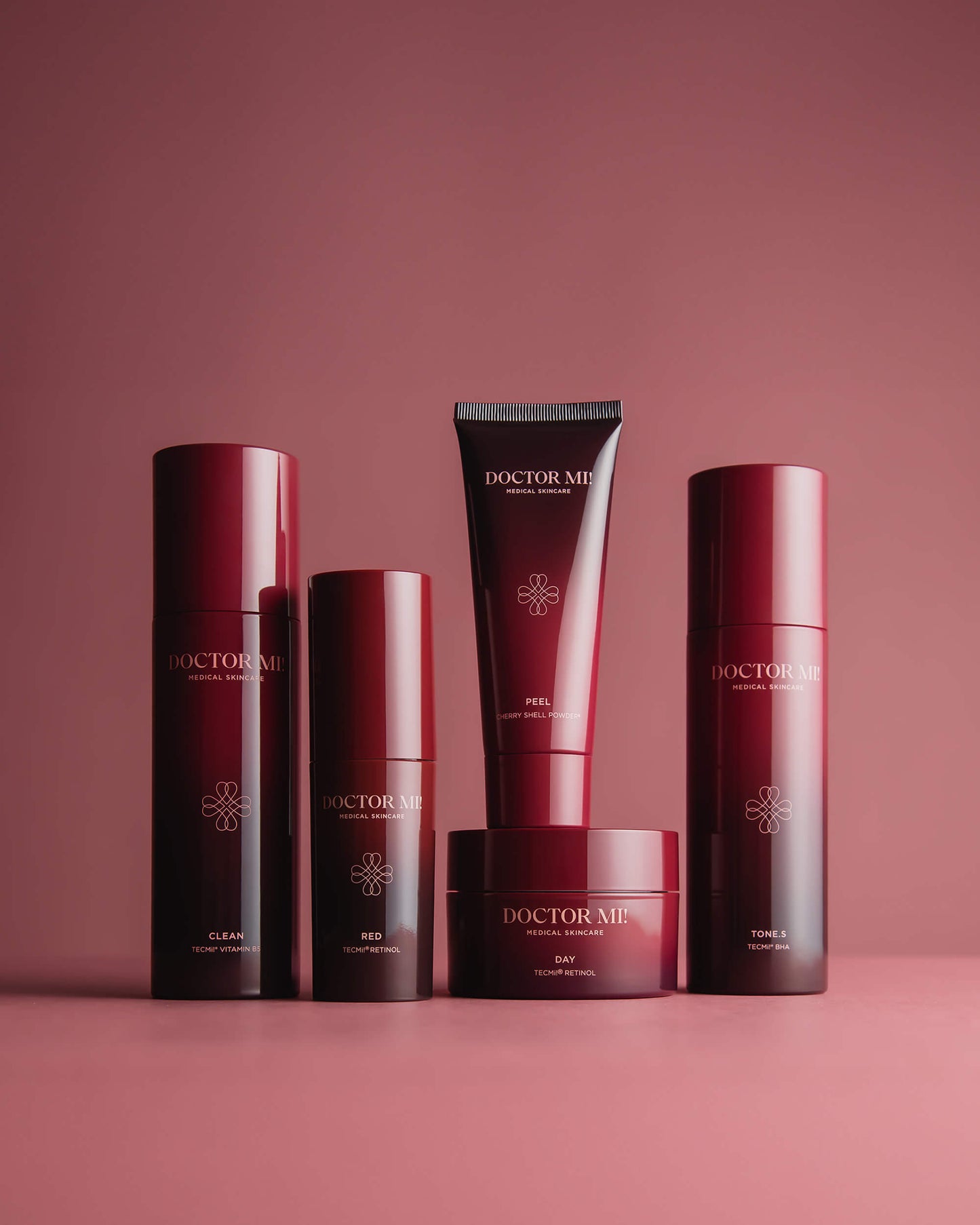 DOCTOR MI! AKNE SET Produktset für zu Akne neigender Haut mit tiefenwirksame und beruhigende Prozesse für ein klares Hautbild dank TECMi!® Retinol mit BALANCING CLEANSER in rotem Pumpspender, REVIVING PEEL in roter Tube, RENEWING TONER in rotem Pumpspender, REFINING DAY CREAM in rotem Tiegel,  RED BOOSTER in rotem Pumpspender auf rotem Hintergrund