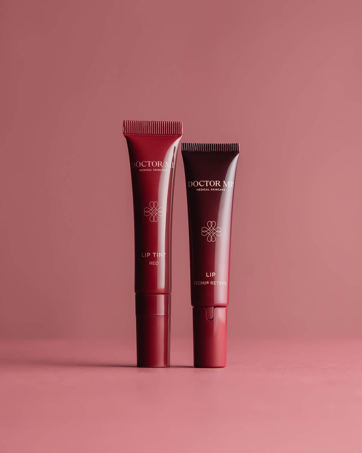 DOCTOR MI! LIP & LIP TINT DUO Intensive Lippenpflege im Set für gepflegte Lippen und einem Hauch von Farbe mit PLUMPING LIP CARE in roter Tube und PLUMPING LIP TINT in roter Tube auf rotem Hintergrund